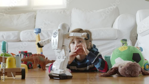 Young blond boy engages with a robot toy in a cluttered room