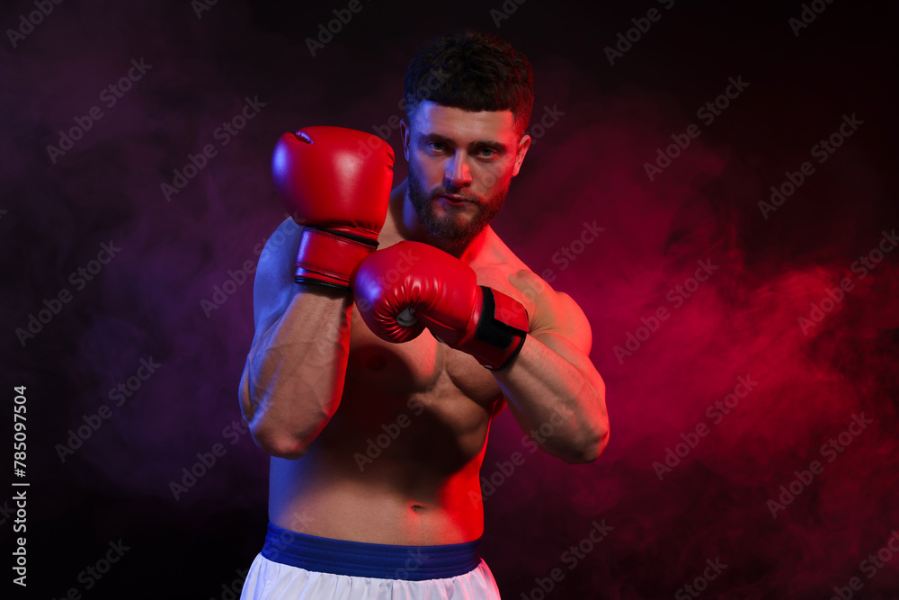 Man wearing boxing gloves on dark background