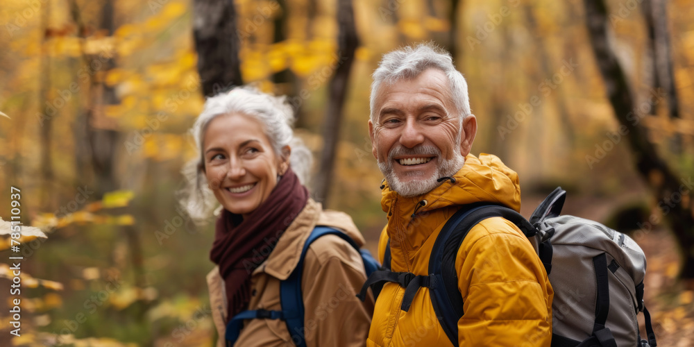 Joyful elderly couple with backpacks enjoying a hike among autumn leaves in the forest. Joyful elderly couple with backpacks enjoying a hike among autumn leaves in the forest.