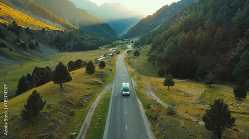 motorhome rides along empty road along green valley, mountains and river, aerial view