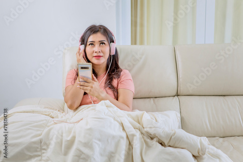 Pretty young Asian woman listening to music with mobile phone