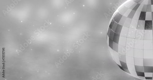 Image of mirror disco ball spinning over spots of lights on grey background