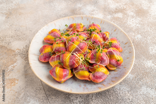 Rainbow colored dumplings with microgreen on brown concrete. Side view
