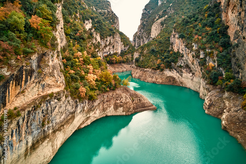 A lake nestled in a canyon, embraced by trees and mountains, under the vast sky