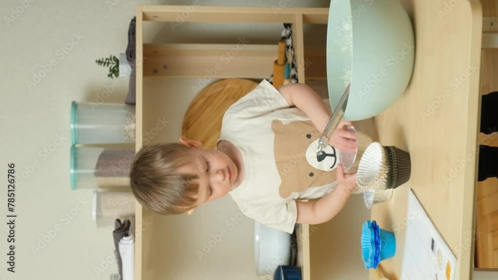 Little boy preparing to cook cupcakes, laying out muffin tins on table, vertical slow motion. Little boy preparing to cook cupcakes, laying out muffin tins on table, vertical slow motion.