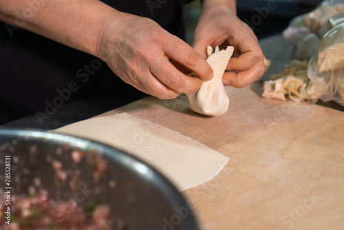 Close-up of female chef's hands sculpting khinkali. Process of cooking khinkali in the kitchen in the restaurant