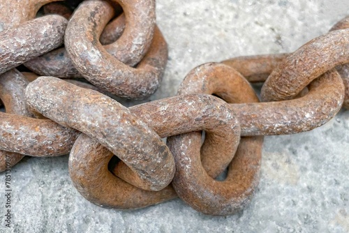 Closeup shot of a rusty iron chain on the gray background © Wirestock