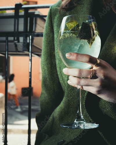 Vertical closeup of female hand holding a glass of fresh hugo