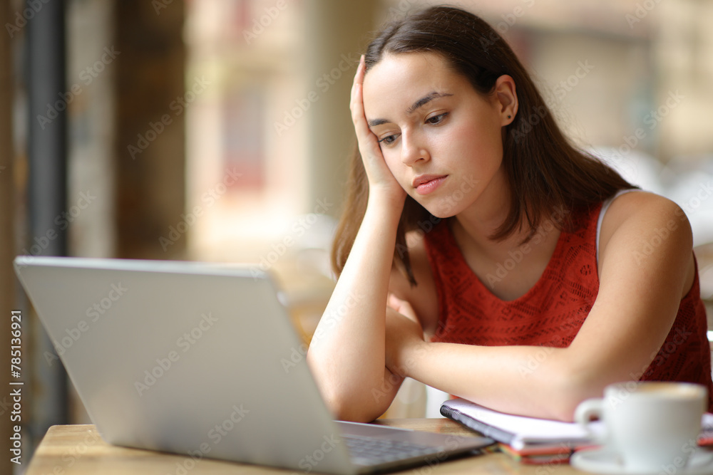 Apathetic student watching online content on laptop Apathetic student watching online content on laptop