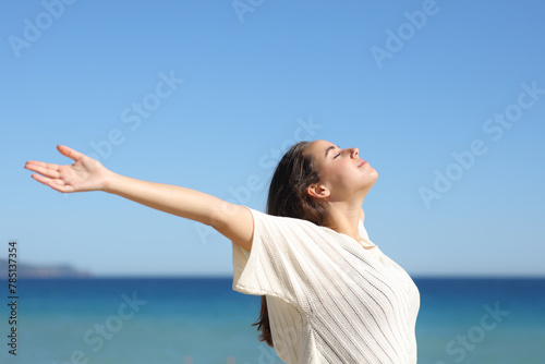 Woman outstretching arms and breathing on the beach photo