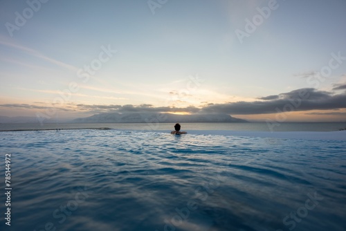 Person in an infinity Swimming Pool At the edge of the Hofsos Village during sunset in Winter photo