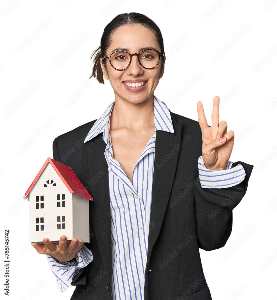 Caucasian businesswoman with house model, real estate concept on studio background showing number two with fingers. Caucasian businesswoman with house model, real estate concept on studio background showing number two with fingers.