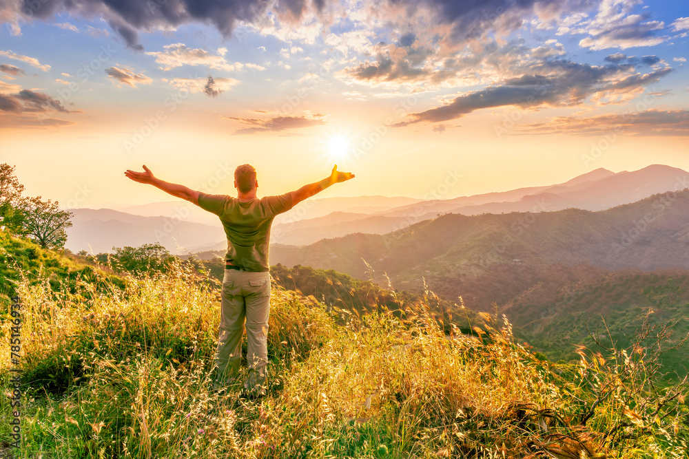 rejoicing man with beautiful scenic mountain sunset landscape on background. happy man watching amazing evening sunset rejoicing man with beautiful scenic mountain sunset landscape on background. happy man watching amazing evening sunset