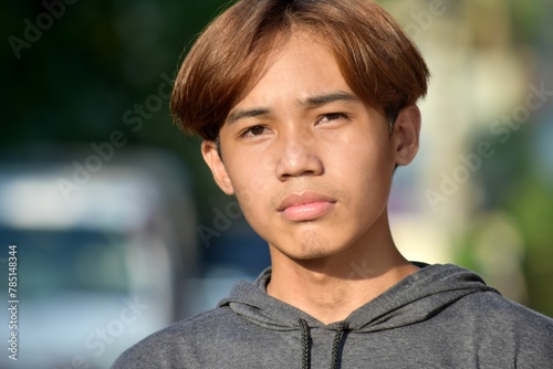 Portrait of a teenage Southeast Asian boy with brown hair in the street © Wirestock