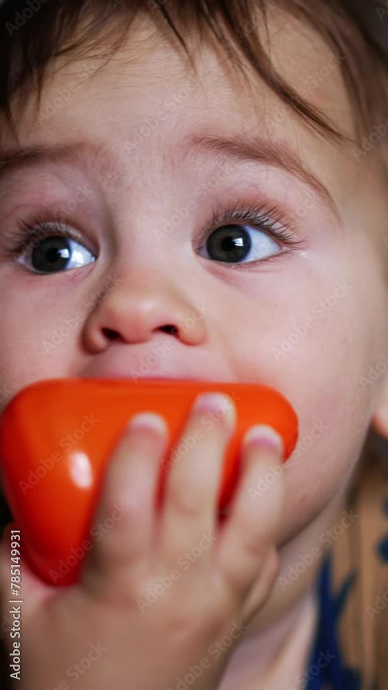 Lovely sweet kid lies on his belly holding a toy in his mouth. Funny baby chewing toys to scratch his gums. Close up. Vertical video Lovely sweet kid lies on his belly holding a toy in his mouth. Funny baby chewing toys to scratch his gums. Close up. Vertical video
