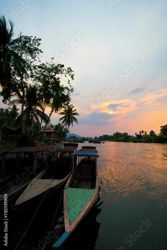 Vertical shot of wooden boats parked in the shore of a lake at a beautiful sunset