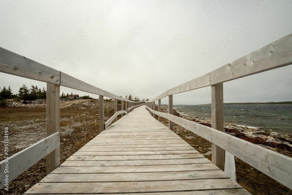 Long empty wooden walkway along the arid lakeshore under white sky