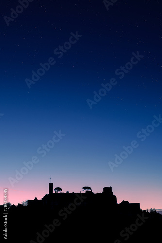 Dawn breaking over the silhouette of the medieval village of Turenne in the Correze department of France with stars overhead