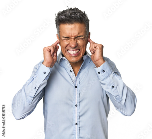 Middle-aged Latino man covering ears with hands.