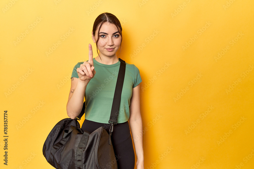 Athletic caucasian woman with sports backpack showing number one with finger. Athletic caucasian woman with sports backpack showing number one with finger.