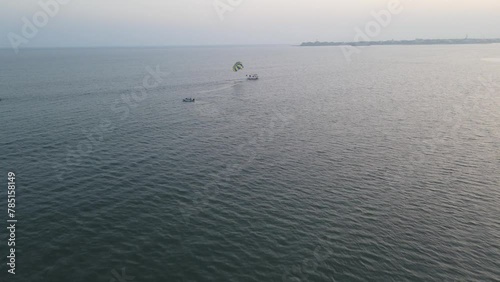 Raising drone shot over a fast Parasailing boatin the sea water at sunset photo