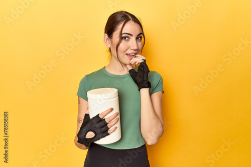 Fit woman holding a protein shake relaxed thinking about something looking at a copy space.