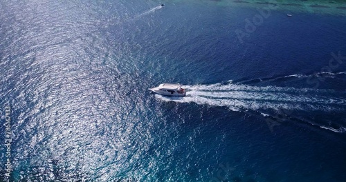 Aerial view of boat floating on sea under blue bright sky