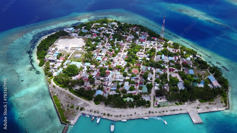 Aerial view of island surrounded by buildings and emerald water in Maldives