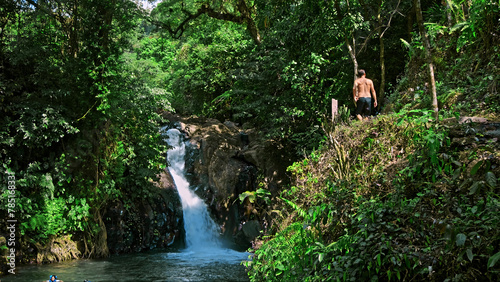 waterfall with rocks among tropical jungle with green plants and trees and water falling down into river