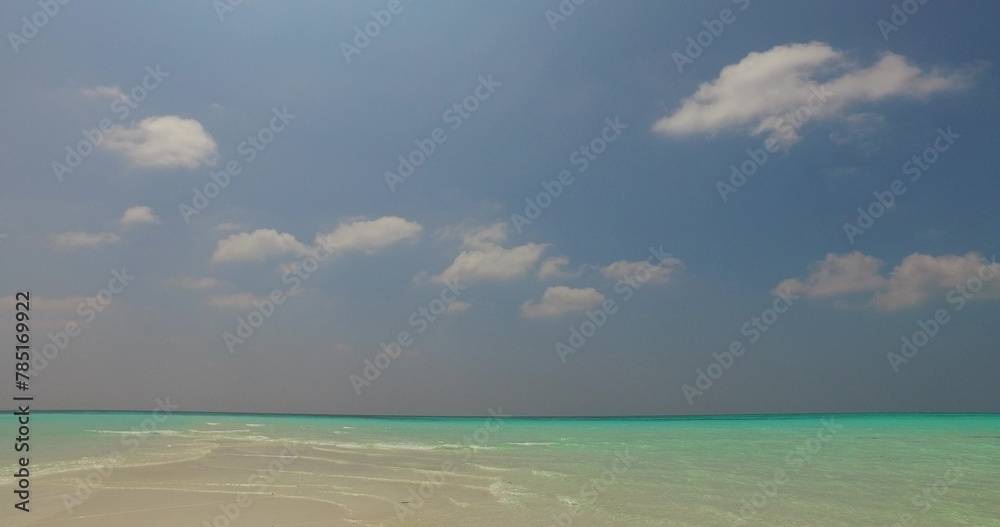 Scenic view of a sandy beach against a turquoise sea on a sunny day