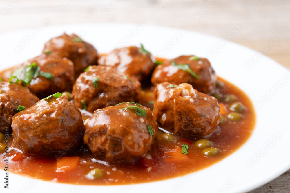 Meatballs, green peas and carrot with tomato sauce on wooden table. Close up Meatballs, green peas and carrot with tomato sauce on wooden table. Close up