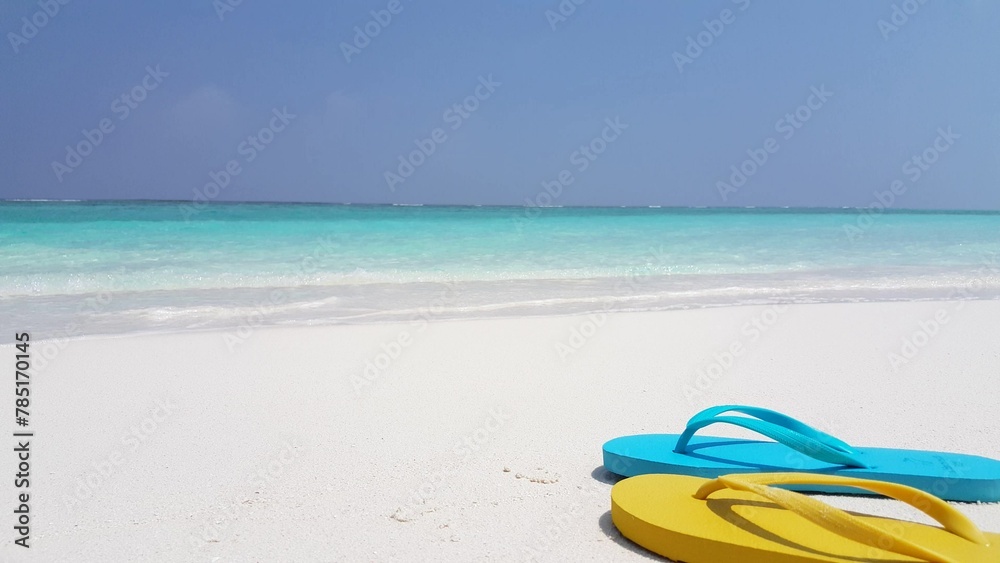 Blue and yellow slippers on the sandy beach Blue and yellow slippers on the sandy beach