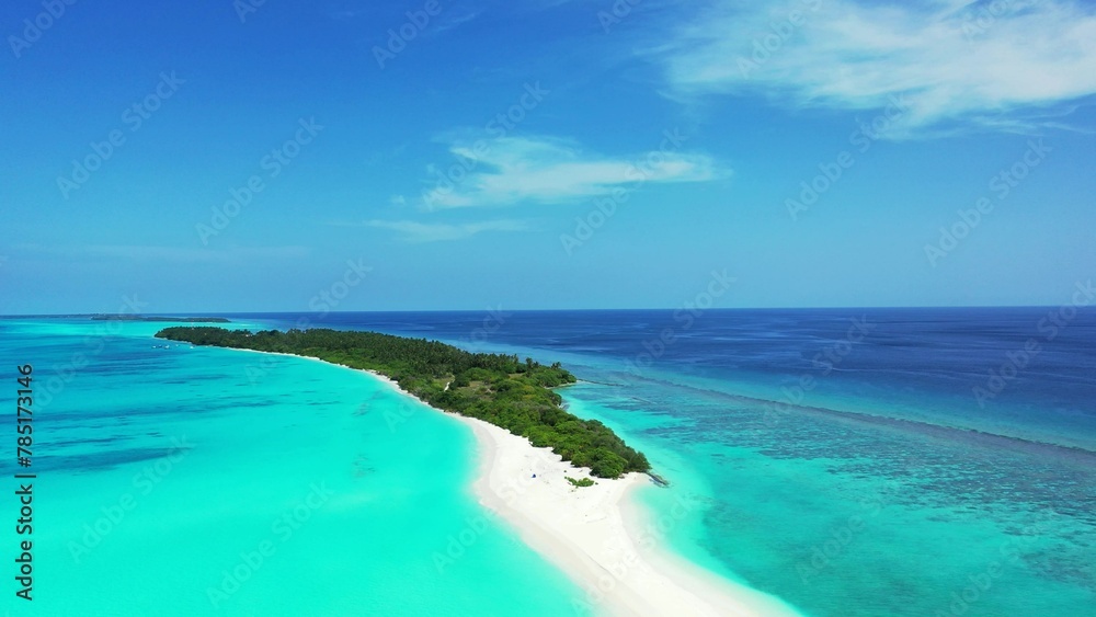 Aerial view of an island covered with greenery against a turquoise sea on a sunny day