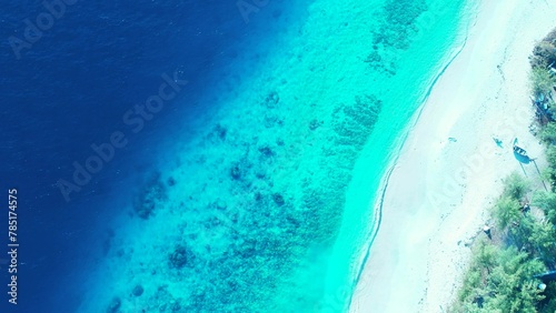 Aerial shot of coral reefs under tranquil water in the sea and a whtie sandy beach