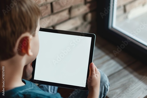 Display mockup from a shoulder angle of a boy holding a tablet with a completely white screen