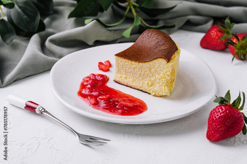 Fototapeta premium Delectable san sebastian cheesecake slice with strawberry sauce