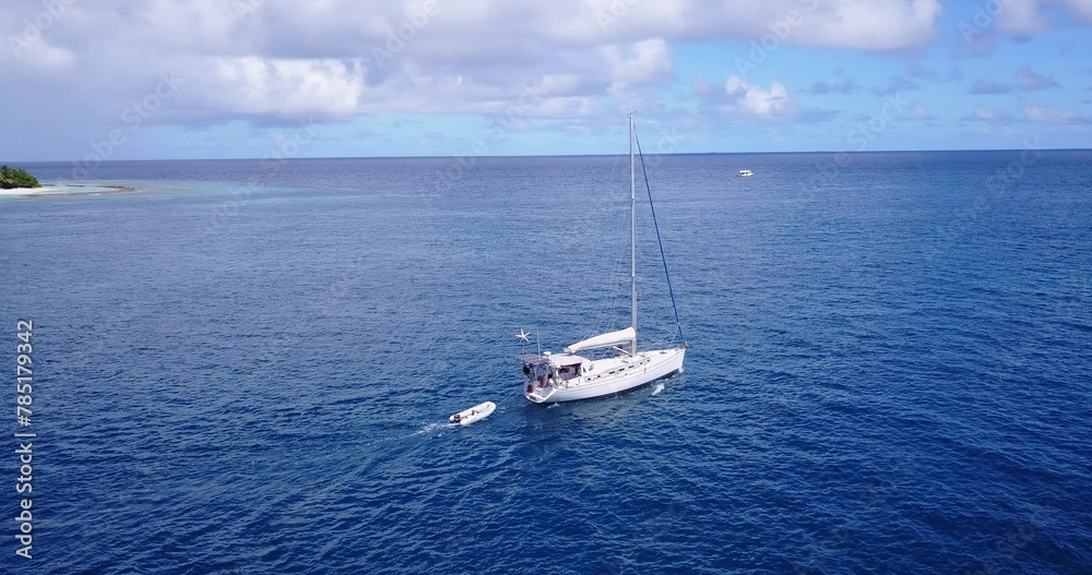 Beautiful shot of a yacht sailing across a deep blue ocean with other boats in the distance Beautiful shot of a yacht sailing across a deep blue ocean with other boats in the distance