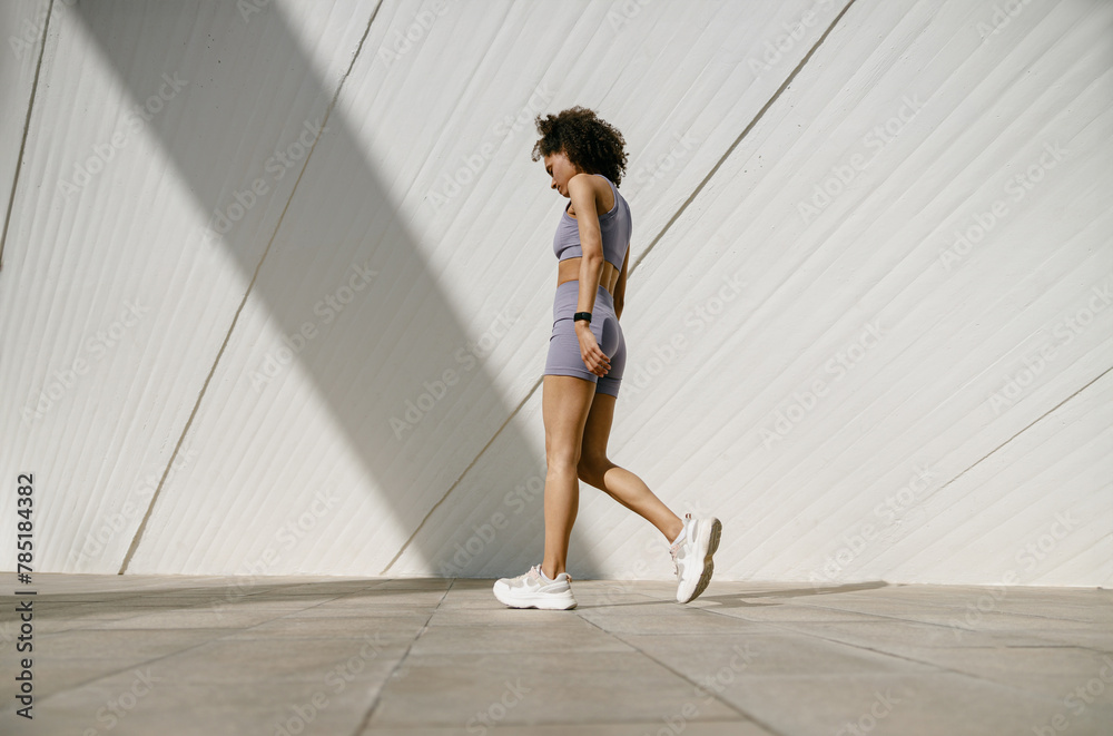 Young woman in tracksuit have rest after workout outside crossing on building background Young woman in tracksuit have rest after workout outside crossing on building background