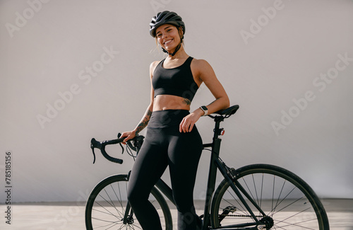 Professional female cyclist in protective gear looking at camera while riding bicycle in city