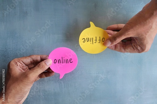 Top view image of hand holding speech bubble with text ONLINE and OFFLINE. photo