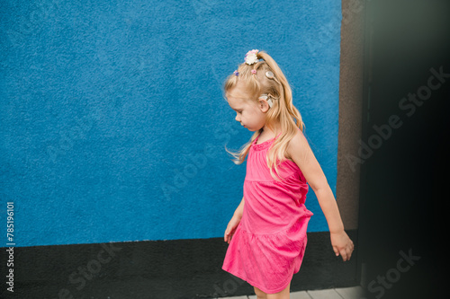 Child girl with hearing aid and cochlear implantation system. Kid with hearing problems walks outdoor in summer. Inclusion and diversity concept. Copy space © satura_