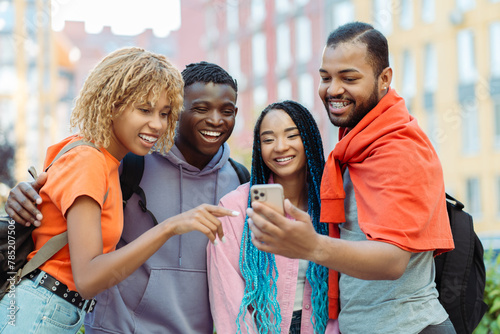 Group of smiling African American friends holding mobile phone, communication