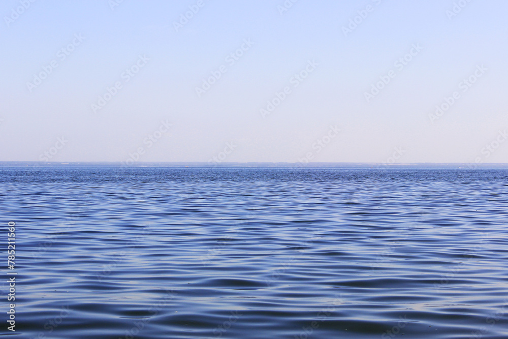 Fototapeta premium Blue sea and blue sky, beautiful waves. View from the beach to the rocky bay Morning light over the sea in Sanremo,
