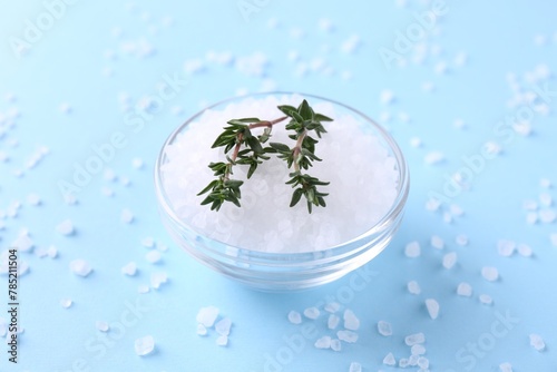 Salt and thyme in bowl on light blue background, closeup