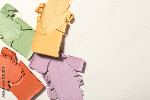 Samples of different color correcting concealers on white background