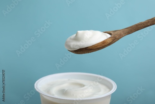 Eating delicious natural yogurt on light blue background © New Africa