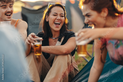 Happy friends laughing and having a good time over beers at a festival camp photo