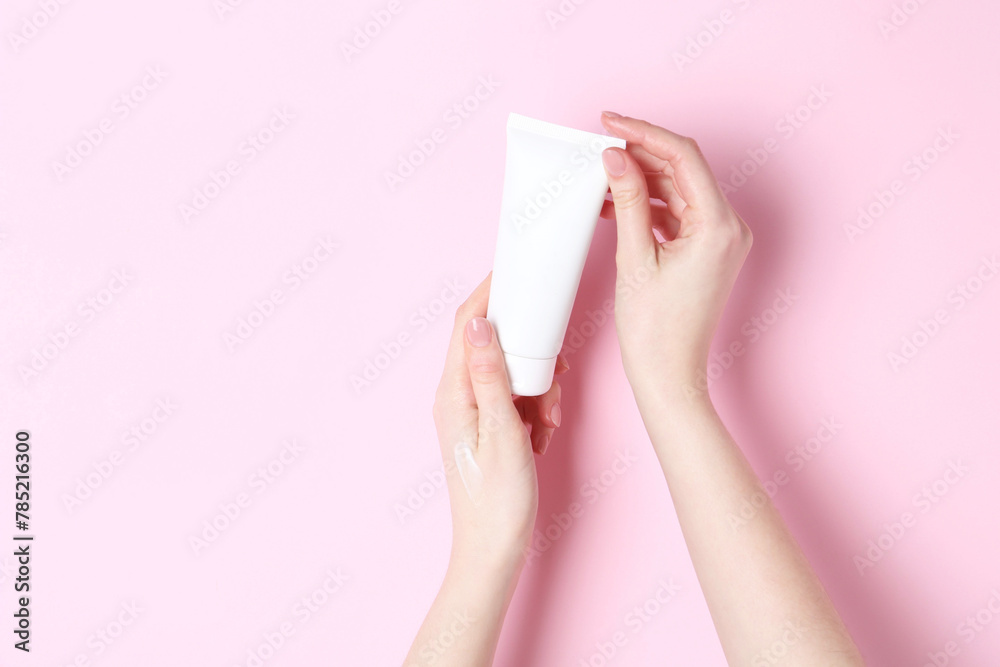 Woman holding tube of cream on pink background, closeup Woman holding tube of cream on pink background, closeup