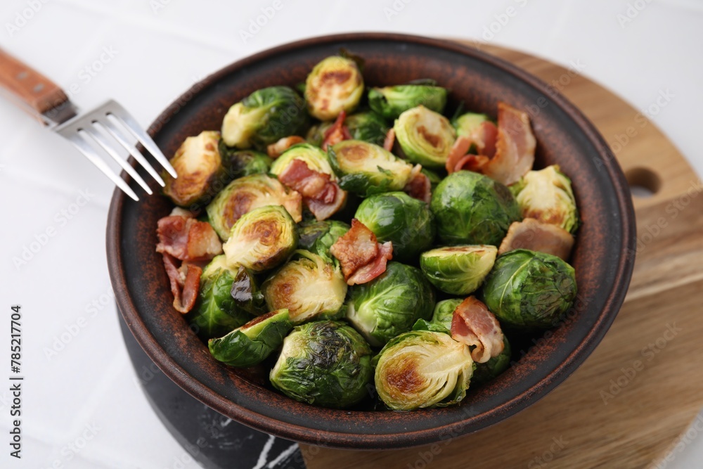 Delicious roasted Brussels sprouts and bacon in bowl on white table, closeup Delicious roasted Brussels sprouts and bacon in bowl on white table, closeup