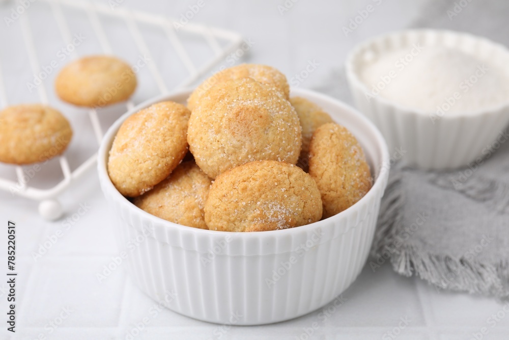 Tasty sugar cookies in bowl on white tiled table, closeup